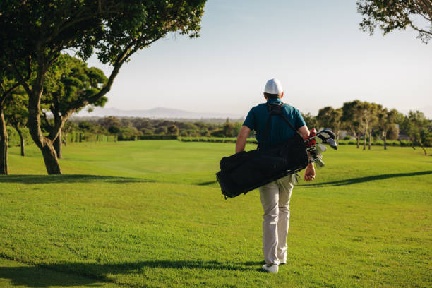 istock Man walking on golf course carrying golf clubs at a resort 2188214492