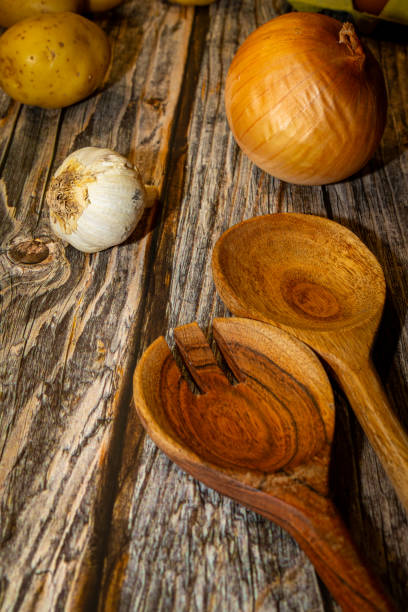 istock Raw garlic potatoes onion and kitchen spoons on wooden table 2188215274
