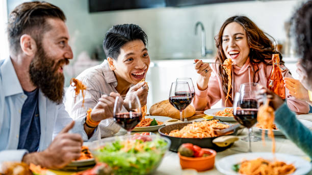 istock Happy multicultural friends having pasta dinner party at home - Multiracial people drinking red wine at lunch break - Food and beverage concept with diverse guys and girls dining together restaurant 2188219835