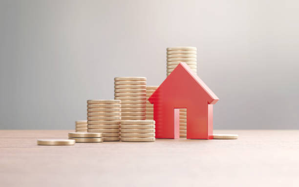 istock Red House Symbol And Gold Colored Coin Stacks Before Defocused Background 2188219845