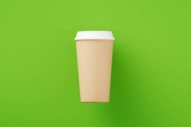 Disposable coffee cup made of craft paper on green background. Horizontal composition with copy space.