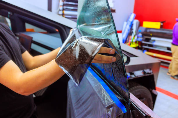 Professional window tint installation in an automotive workshop during daylight hours