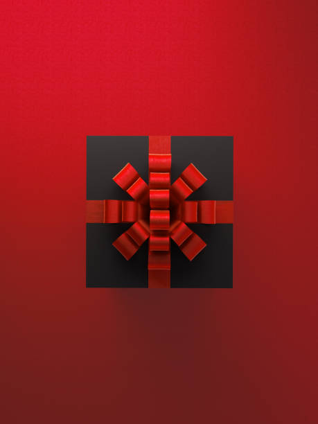 Black gift box with red ribbon over red background. Vertical composition with copy space. Valentine's Day concept.