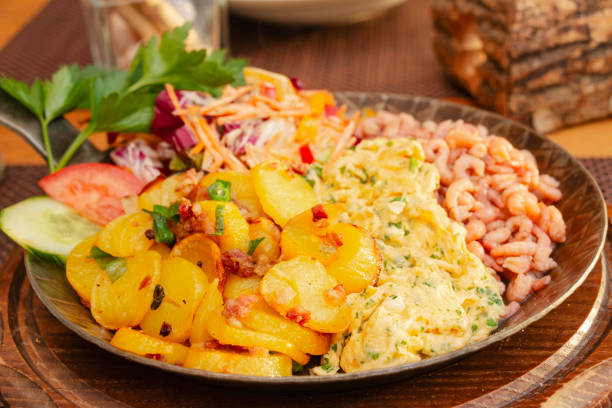 Delicious portion of North Sea shrimps with scrambled eggs and fried potatoes, garnished with salad, served in a hot pan.\nA North German delicacy, especially in the East Frisia region.