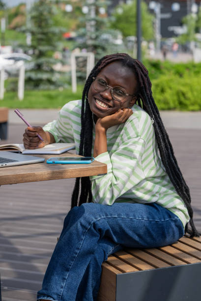 istock Smiling African American woman studying outdoors with notebook and laptop at a park table 2188222404
