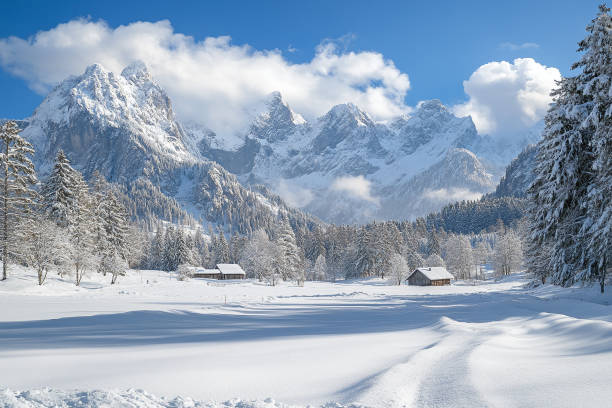 A pristine snow-covered valley surrounded by towering mountains, with sunlight illuminating the serene alpine landscape.