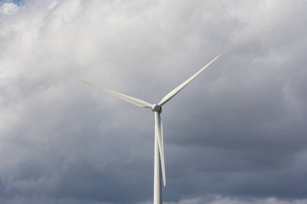 A solitary wind turbine spins gracefully against a dramatic cloudy sky