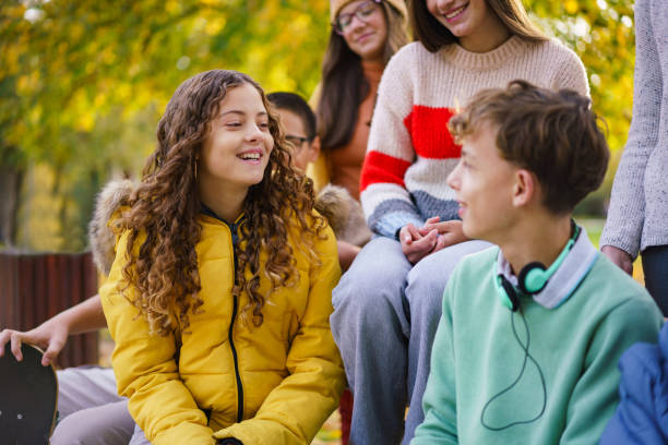 istock Happy teenagers sitting and talking on a bench 2188228558