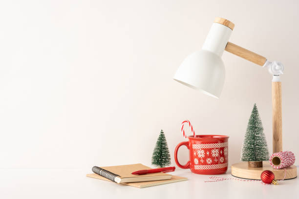 istock A side view minimal Scandinavian workspace featuring a desk lamp, festive red mug, tiny Christmas trees, and stationery. The scene evokes warmth and holiday spirit in a simple and elegant style 2188235970