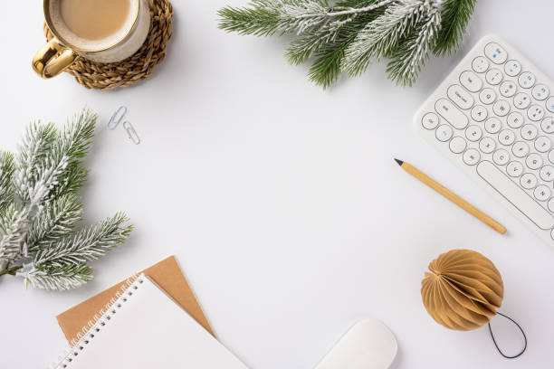 istock Top view of a winter-themed workspace featuring a coffee cup, keyboard, notebook, and festive decor with pine branches. Ideal for illustrating cozy office environments during the holiday season 2188236002