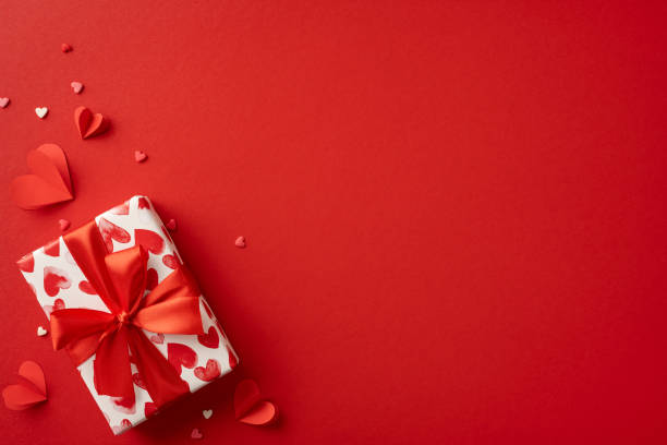 istock Gift wrapped in heart-patterned paper with a red ribbon, adorned with small red hearts. Ideal for Valentine's Day celebrations, conveying love and romance 2188236007