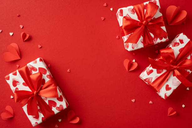 istock Heart-themed Valentine's Day presents with red ribbons on a red background, surrounded by small paper hearts. Perfect for celebrating love and romance during the festive Valentine's season 2188236034