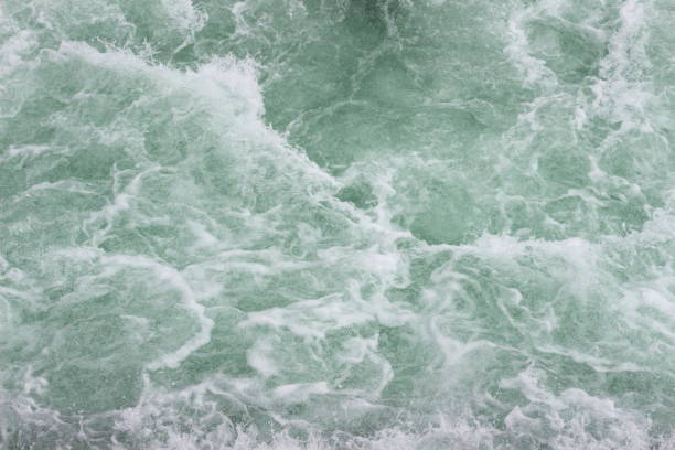 An artistic and abstract close-up of turbulent waters in motion, capturing the dynamic interplay of light, shadow, and ripples
