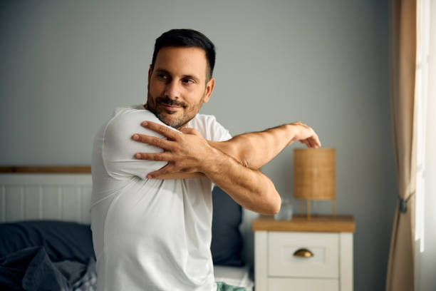 istock Smiling man stretching while waking up in bedroom in the morning 2188240145