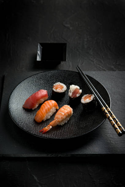 istock mix sashmi and sushi with chopstick over black stone 2188240278