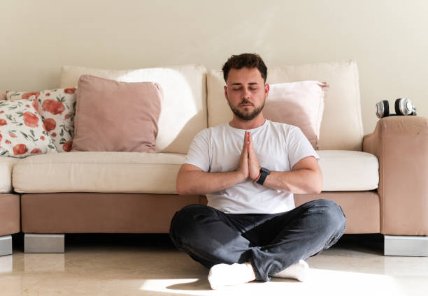 istock Young man meditating peacefully in his living room 2188243803