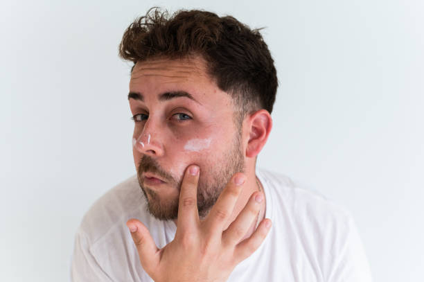 istock Young man applying sunscreen cream on his face for sun protection 2188243896