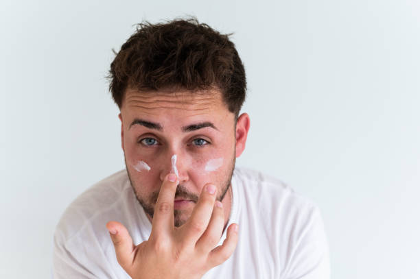 istock Young man applying moisturizing cream on his face 2188243904