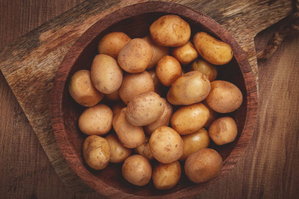 istock Freshly harvested small potatoes in a wooden bowl on a rustic surface with natural textures and colors 2188244318