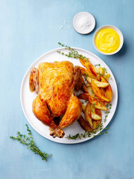 istock Roasted chicken with potatoes on white plate. Blue background. Top view. 2188248292