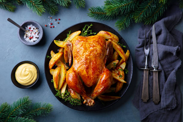 istock Roasted chicken with potatoes on dark plate. Christmas dinner. Grey background. Close up. Top view. 2188248399