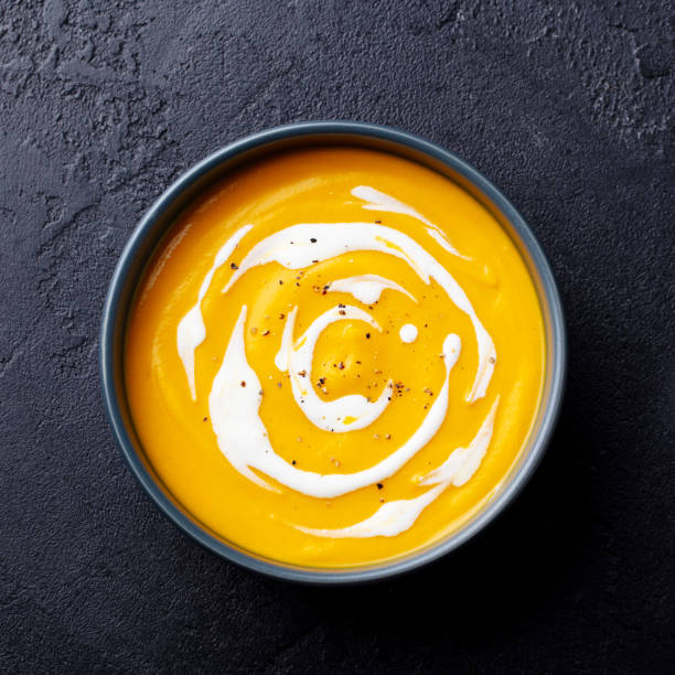 istock Butternut squash soup with cream in black bowl. Dark background. Close up. Top view. 2188249096