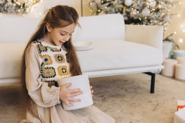 istock Curious girl opening christmas gift box near decorated tree 2188253486