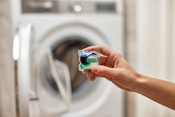 istock female hand putting laundry capsule into washing machine 2188256616
