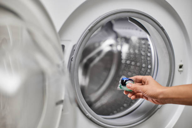 istock female hand putting laundry detergent capsule into washing machine 2188256621