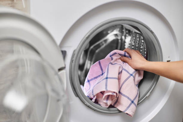 istock Woman putting clothes into the washing machine 2188256624