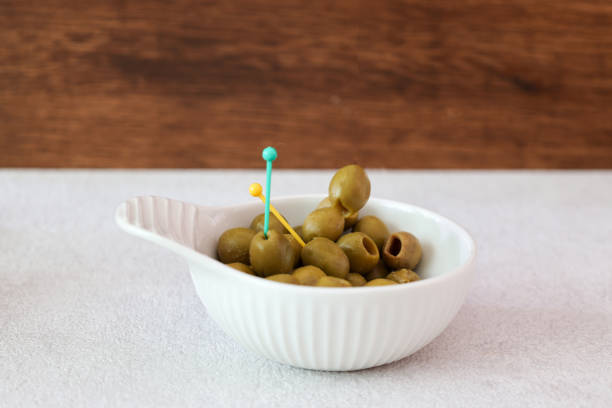 Pickled olives in a bowl on a white table.