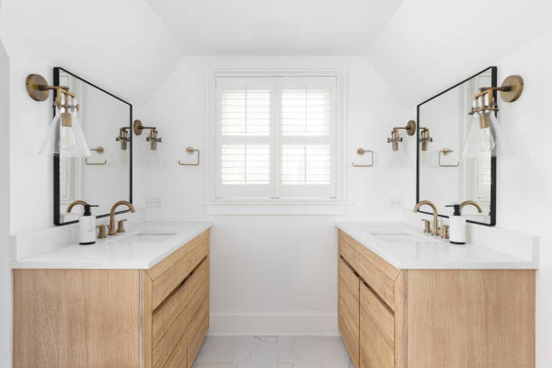 istock A bathroom with white oak cabinets and gold faucets and sconces. 2188262455