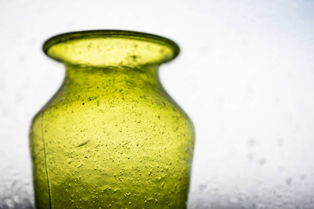 Green hand made glass vase in a window.
