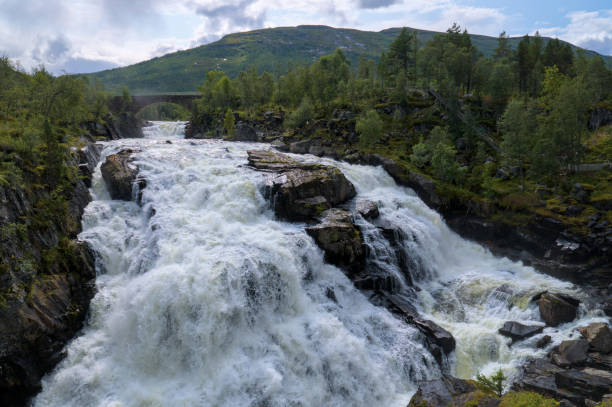 istock This image showcases a powerful waterfall cascading over rugged rocks, surrounded by lush greenery. 2188266253