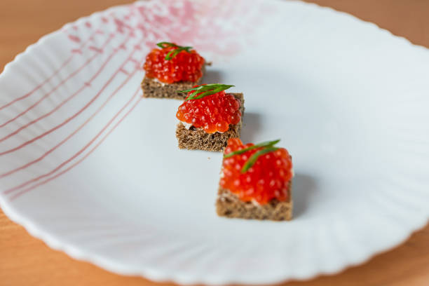 Delicious sandwiches topped with red caviar on a wooden table, illuminated by natural sunlight. Perfect for themes of gourmet food, luxury, festive meals, and elegant appetizers