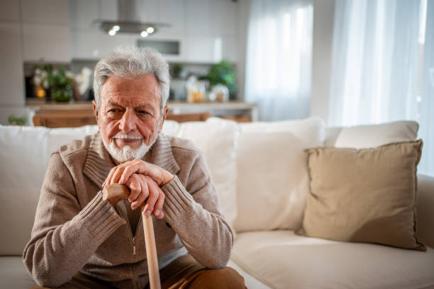 Senior man relaxes on the sofa, leaning on his walking cane. This peaceful moment symbolizes comfort, stability, and the tranquility of senior life. Ideal for themes of aging, independence, and retirement.