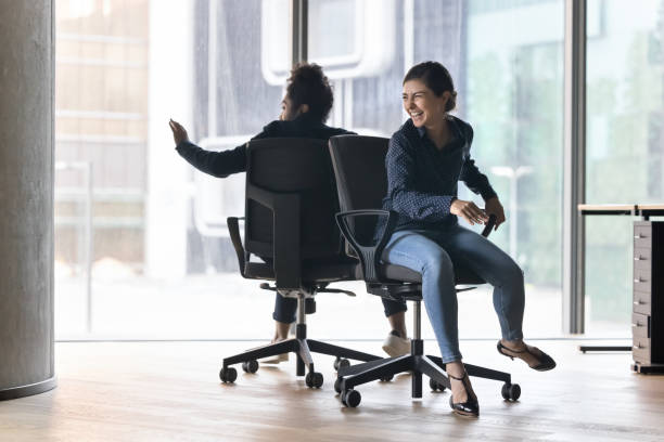 istock Cheerful Indian office employee riding seated on chairs 2188277368