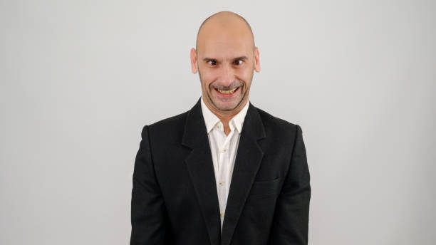 istock In a studio setting, a middle-aged businessman wearing a suit is standing in front of a white background, making funny facial expressions and looking at the camera 2188280366