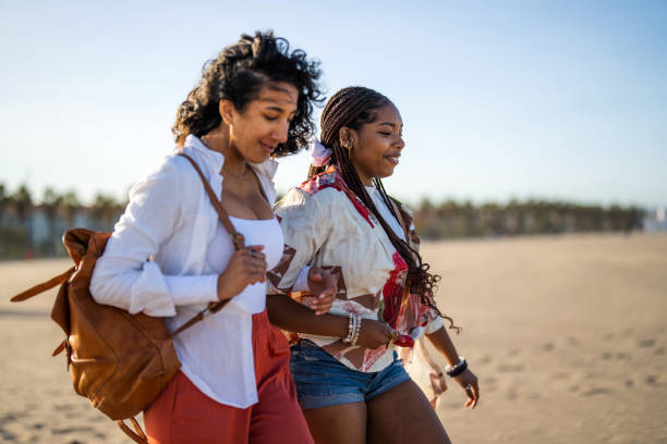 Kendwa, Zanzibar - October 4, 2019: Local women in traditional dress going along the ocean shore during low tide. Tanzania, Africa