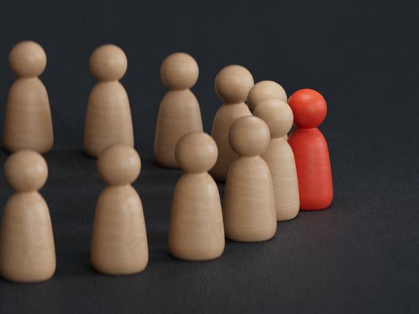 istock A 3d concept graphic depicting a red person standing out from the crowd concept. Rendered against a white background with a soft shadow and reflection to enhance the 3D. 2188291316
