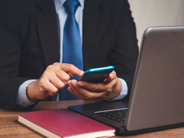 istock Businessman in suit using smartphone at desk with laptop. 2188307098