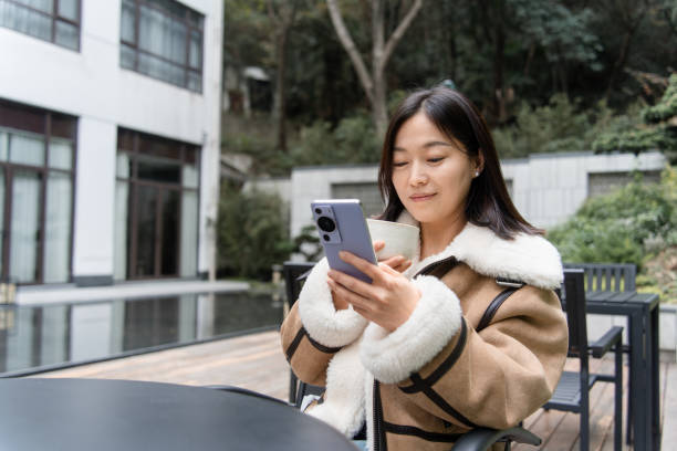 istock asian female using smart phone outdoor with coffee 2188309343