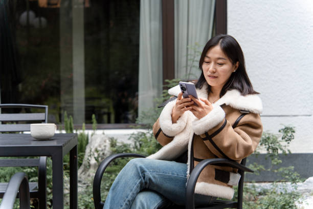 istock asian female using smart phone outdoor with coffee 2188309434