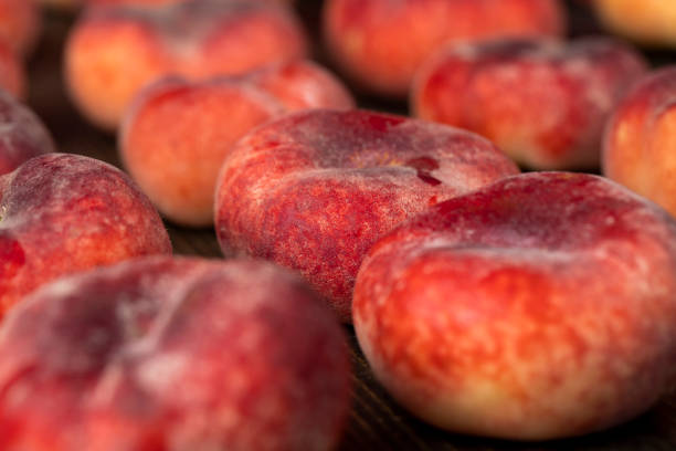 a pile of ripe washed peaches on the table, flat ripe and soft peaches after washing, some in drops of water