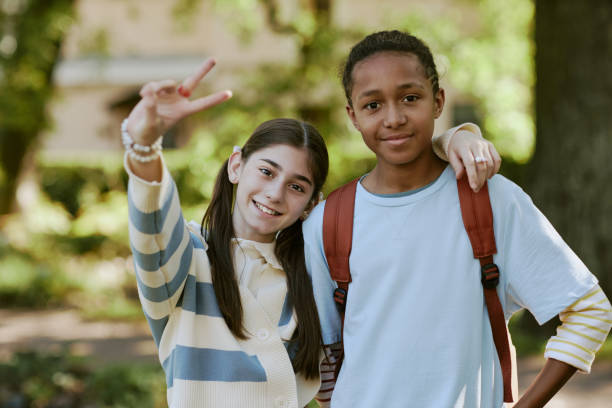 Ethnically diverse teen boy and girl wearing casual clothes having fun posing for portrait outdoors