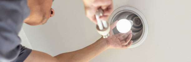 istock Power saving concept. Hands holding new Light Emitting Diode ( LED ) light bulb with light on and blur spiral compact-fluorescent (CFL) bulbs behind for copyspace. 2188314271