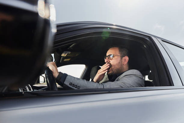 istock Tired businessman yawning while driving a car. 2188318358