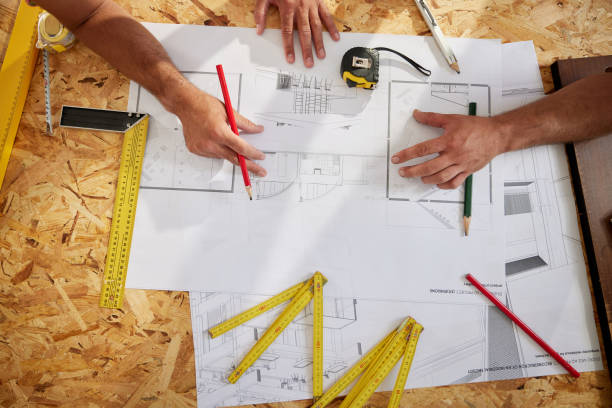istock Above view of manual workers examining blueprints on construction site. 2188318859