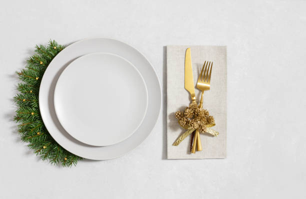 istock Festive table setting with empty beige plate, gold cutlery and fir branches on white background. Beautiful serving for Christmas dinner. Top view, flat lay. 2188321212