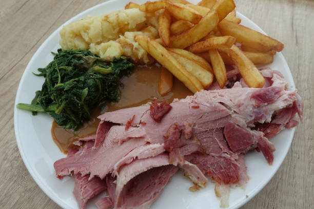 Sliced ​​cooked ham on the bone served with French fries, cooked spinach, mashed potatoes and a Madeira sauce  French Cuisine